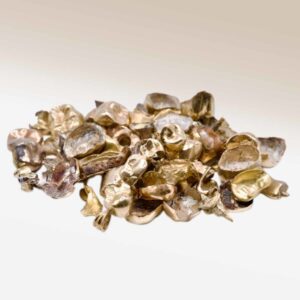Assorted dental gold scrap pieces including crowns, bridges, and inlays on a white surface for precious metal recovery