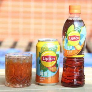 Glass of iced lemon tea with fresh lemon slices and mint leaves on a wooden table