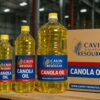 Premium refined canola cooking oil in a clear PET bottle, bright golden-yellow liquid being poured into a pan with vegetables; non-GMO and heart-healthy label, high smoke point for deep frying.